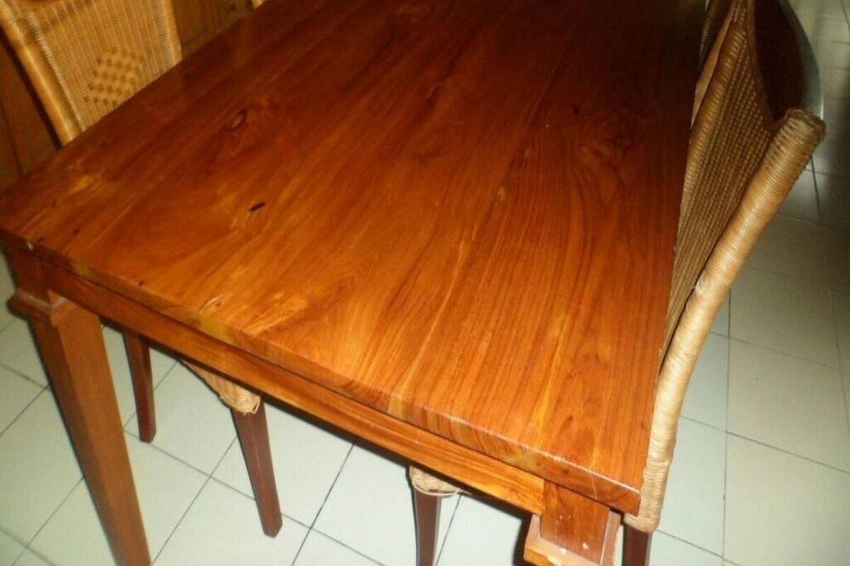 A wooden dining table with chairs, a sofa, and a TV in a living room.