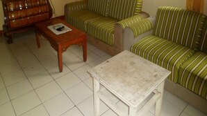 Un salón con un conjunto de sofás, una mesa de centro de madera y un televisor.