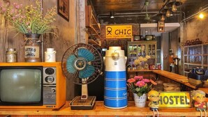 A vintage-themed room with a vintage television, a large blue fan, and various decorative items including flowers and a sign that reads "CHIC". - Ok Chic Phuket Hostel (Phuket)