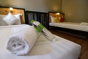 A neatly made bed with a rolled white towel and a clear plastic bottle on it. - Ok Chic Phuket Hostel (Phuket)