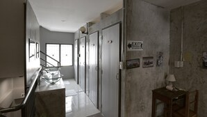 A hallway with a staircase, exit sign, and a small table with a lamp. - Ok Chic Phuket Hostel (Phuket)
