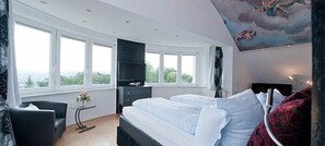 A bedroom with a bed, a TV, a window, and a painting on the wall. - Hotelpension Vitalis (Bad Hersfeld)