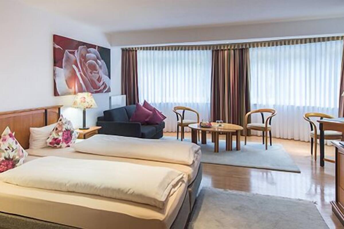 Ein Hotelzimmer mit zwei Betten, einer Couch, einem Fernseher und einem Essbereich.