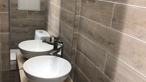 Un baño moderno con dos lavamanos grandes, un inodoro y un espejo.