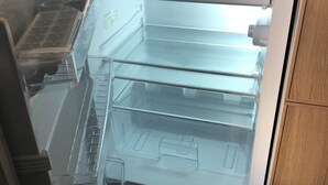 Un refrigerador vacío con varios estantes y un compartimento congelador.