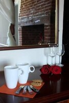Una mesa con dos tazas blancas, un plato de galletas y tres rosas rojas.