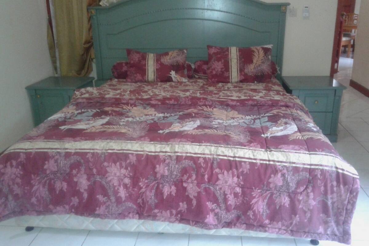 A bed with a floral bedspread, two matching pillows, and a green headboard.