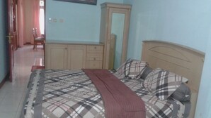 A bedroom with a bed, a wardrobe, a mirror, and a door leading to another room. - Kota Bunga BB (Cipanas)