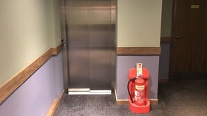 A hallway with a closed elevator, a fire extinguisher, and a door. - The Buchan Hotel (Ellon)