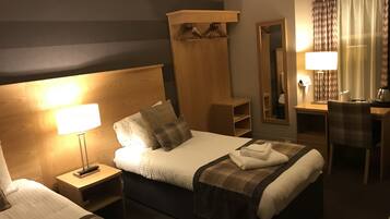 A hotel room with a large bed, bedside tables, a desk, a chair, a mirror, and a wardrobe.