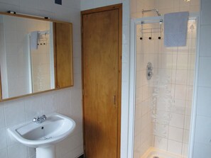 Bathroom features a pedestal sink, glass-enclosed shower, and a towel rack.
