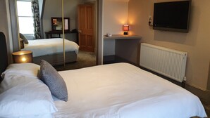 A hotel room with a bed, a mirror, a TV, a lamp, and a radiator. - House by the Harbour - Nc500 Route (Wick)