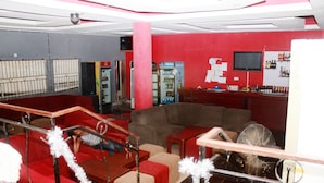 Un espace bar aux couleurs rouge et gris, avec un téléviseur et une variété de bouteilles exposées sur des étagères.