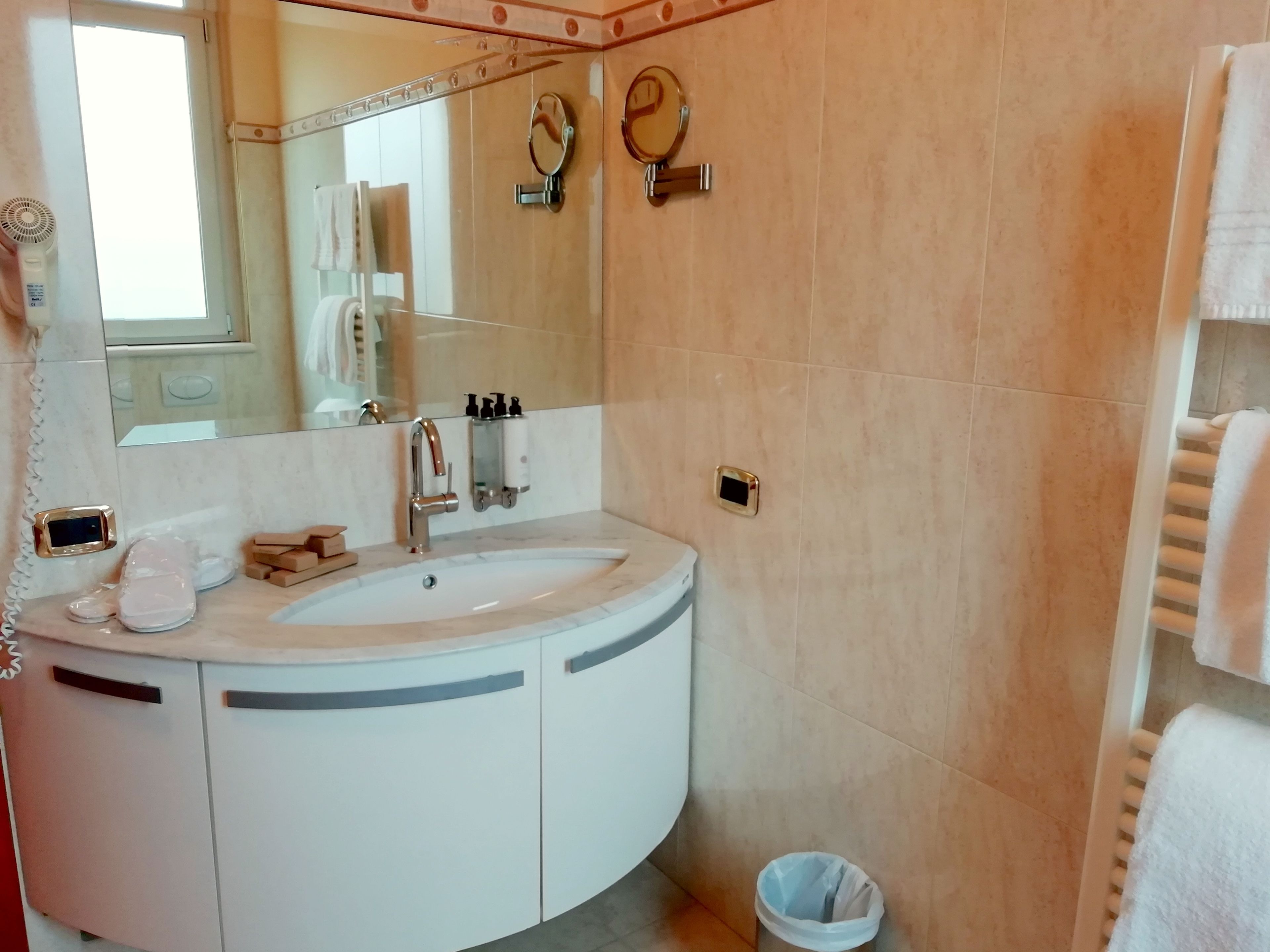 Ein Badezimmer mit einem weißen Waschbecken, einem Spiegel, einem Handtuchhalter und einem Papierkorb.