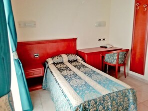 A small, compact room with a single bed, a desk, and a chair. There is a wardrobe with a mirror and a door. - Hotel Concorde (Sant'Egidio alla Vibrata)