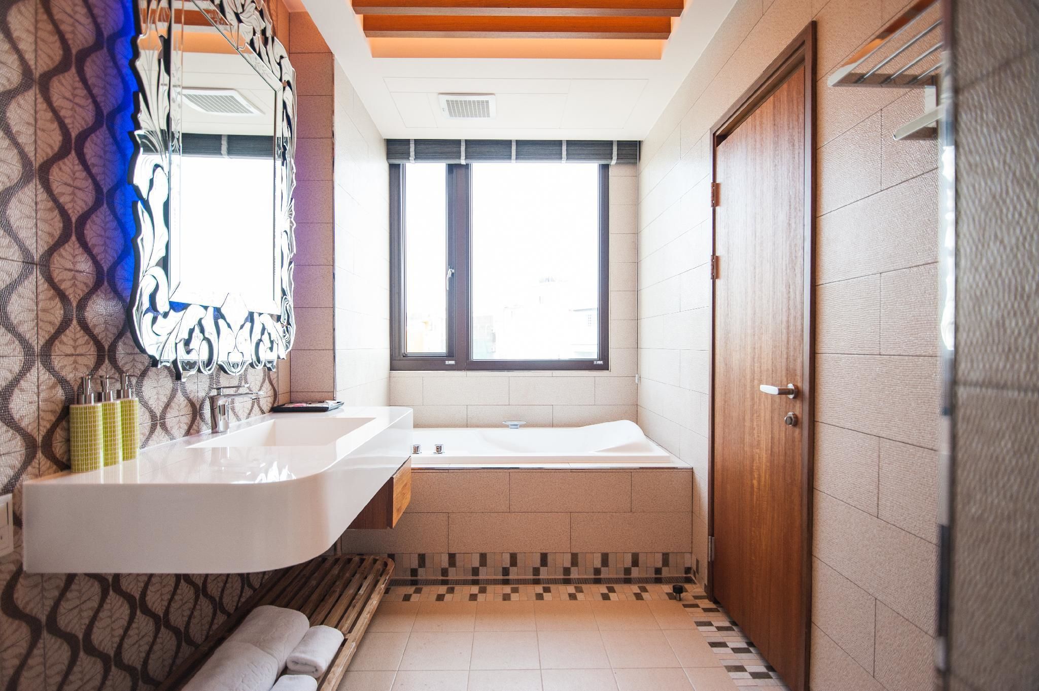 A modern bathroom with a large mirror, a sink, and a bathtub.