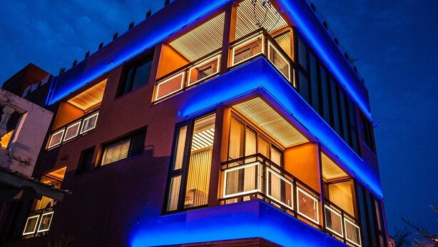 A multi-story building with balconies and large windows, illuminated by blue and warm lighting. - Dreamer Boutique Hotel (Hengchun)