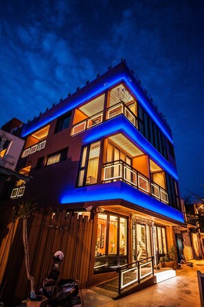 A multi-story building with balconies and large windows, illuminated by blue and warm lighting. - Dreamer Boutique Hotel (Hengchun)