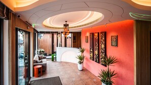 A hotel lobby with a curved reception desk, seating area, and a modern ceiling design. - Dreamer Boutique Hotel (Hengchun)