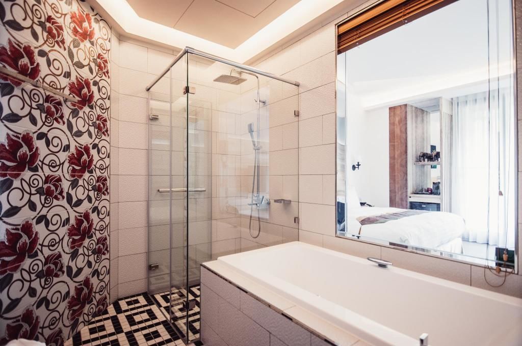 Une salle de bain moderne avec une douche à l’italienne en verre, un grand miroir et une baignoire blanche.