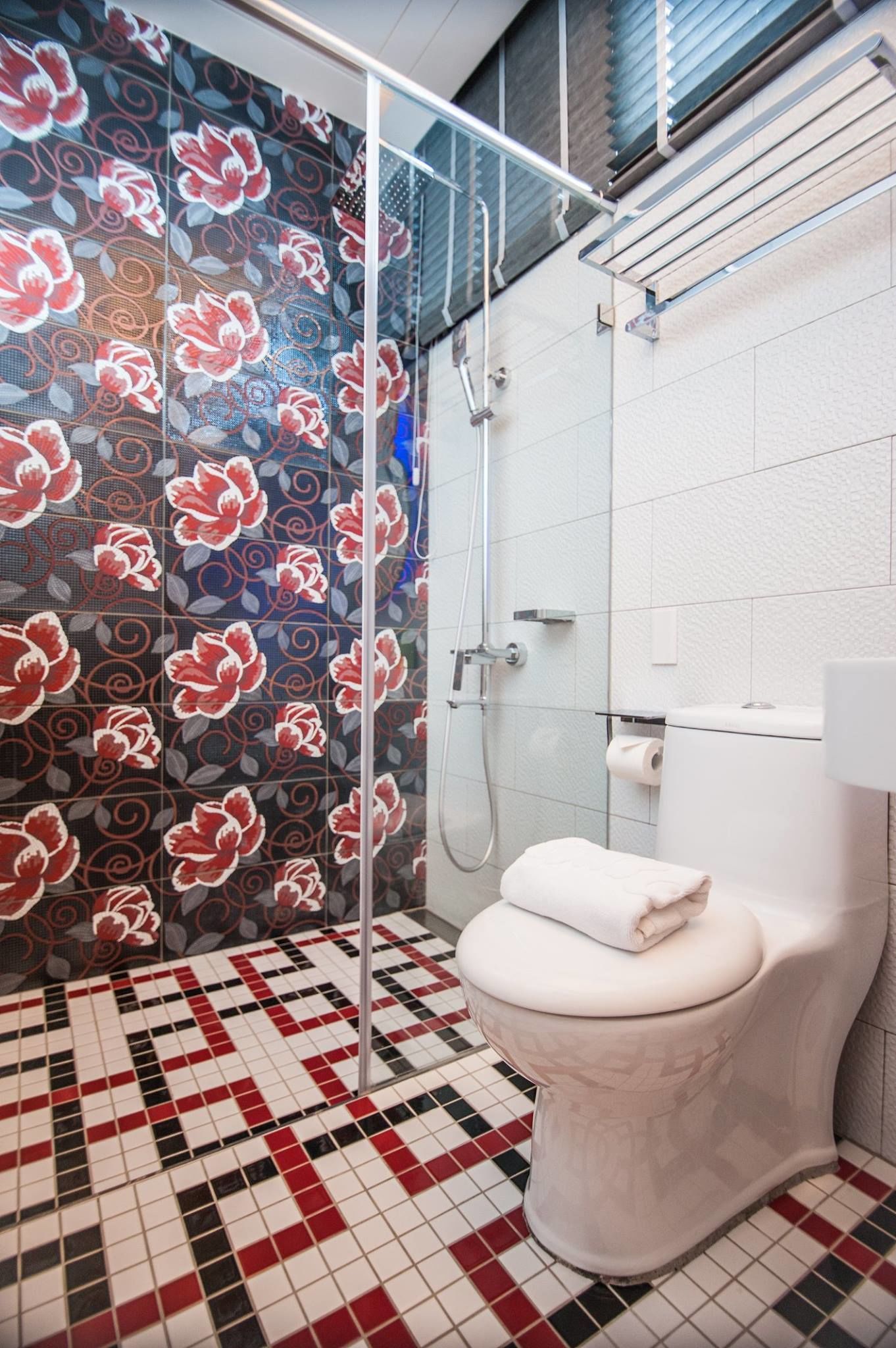 A bathroom with a shower, toilet, and patterned tiles.