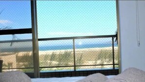 Ein Zimmer mit großem Fenster und Blick auf einen Strand.