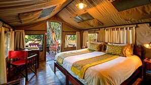 Een tentkamer met een groot bed, een houten bureau en een stoel.