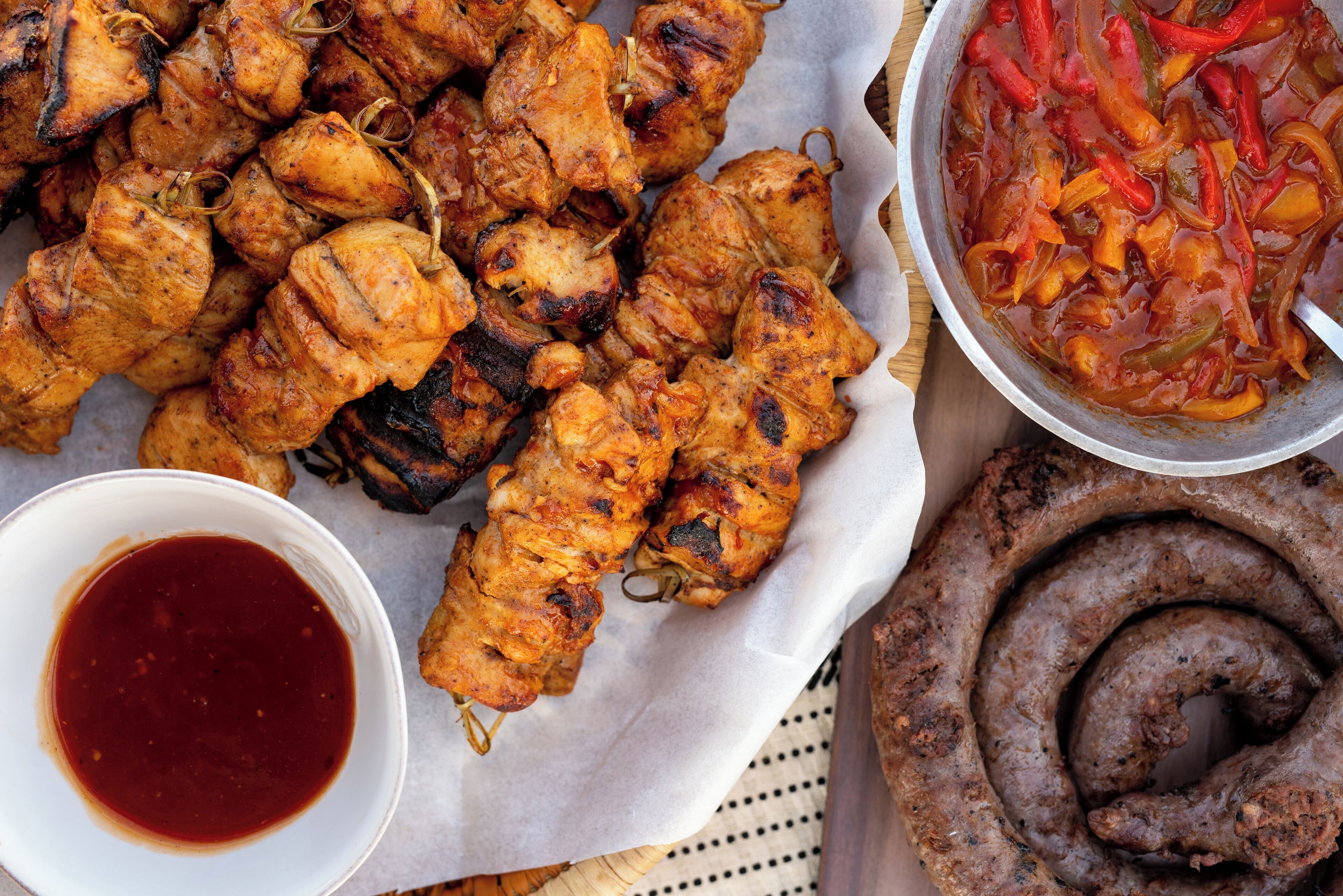 Grillworstjes, een schaaltje saus en een worst op een tafel.