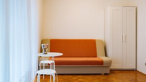 A room with a sofa, a small round table, a cabinet, and a window with curtains.