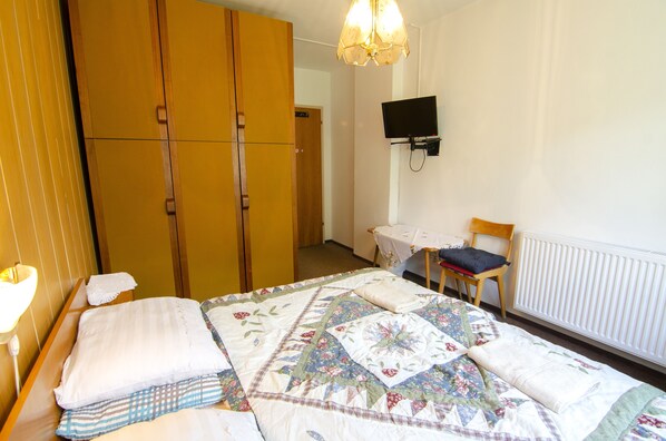 A bedroom with a bed, a wooden wardrobe, a television mounted on the wall, and a chair. - Apartments & Rooms Banich (Kranjska Gora)