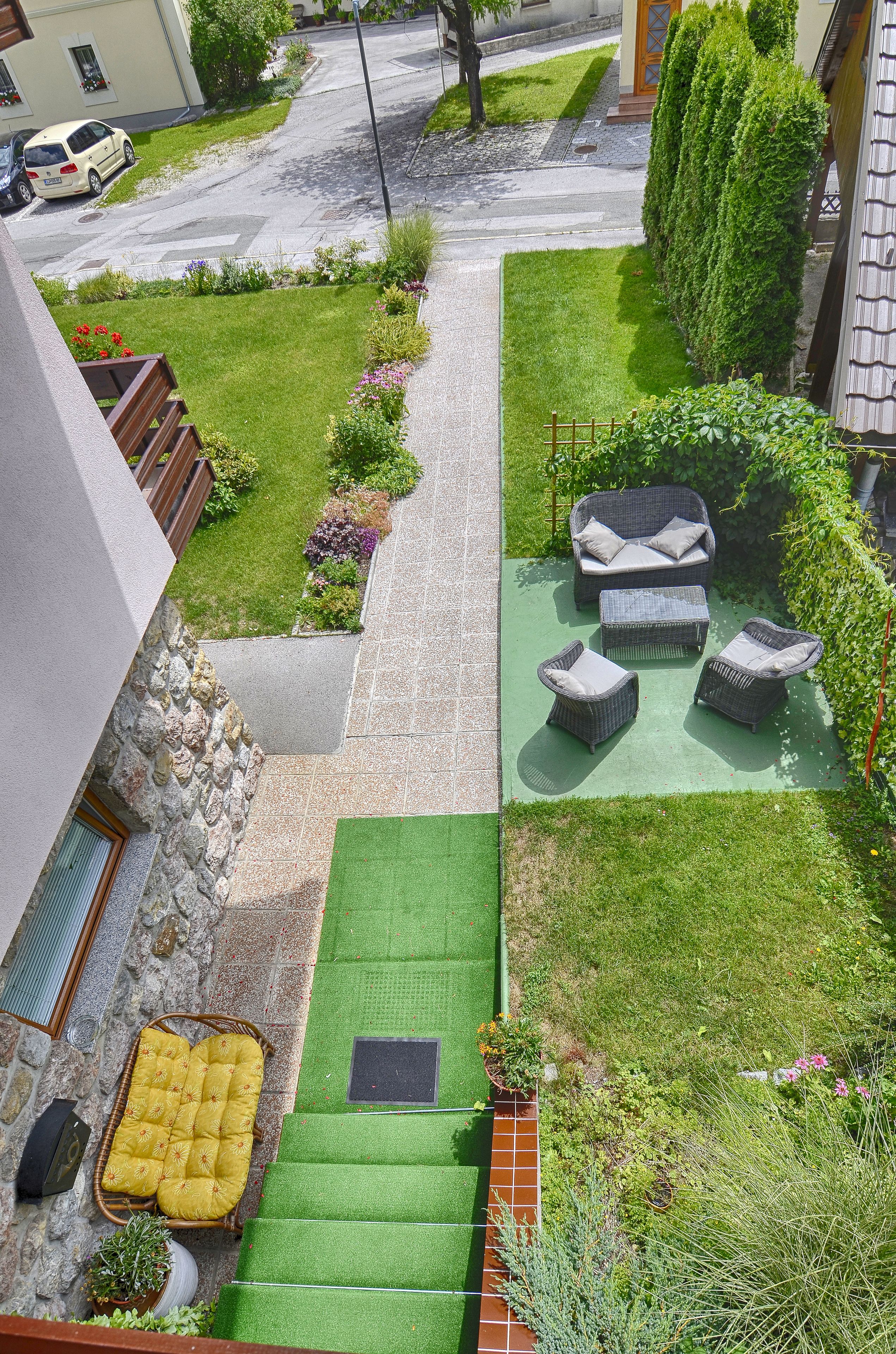 A rooftop garden with outdoor furniture, a stone wall, and a view of the street.