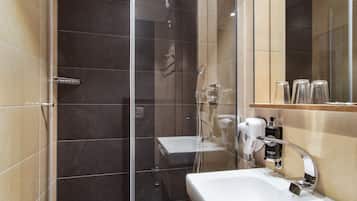 Un baño moderno con ducha envuelta en vidrio, un lavamanos blanco y un espejo sobre él.