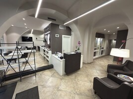 A modern interior with a reception desk, seating area, and a kitchen in the background.