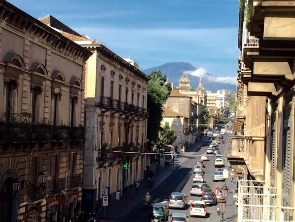 A street view with historic buildings, a mountain in the background, and parked cars. - Etnea 454   Catania Luxury Rooms (Catania)