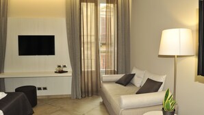 A modern hotel room with a sofa, a flat-screen TV, a lamp, and a potted plant. - Etnea 454   Catania Luxury Rooms (Catania)