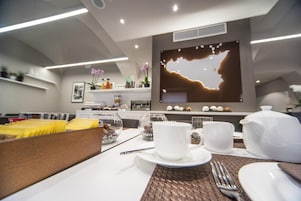 A modern dining area with a table set for breakfast, including plates, cups, and a teapot.