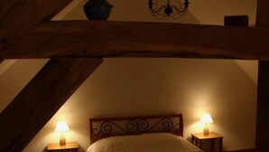 Un dormitorio ático acogedor, con techo de madera, una cama con colcha estampada y dos lámparas de noche.