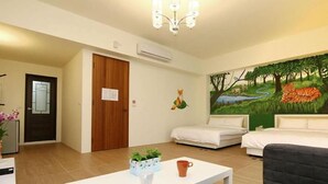 A hotel room with two beds, a painting of a forest scene, a white coffee table, and a small plant. - Rose Cottage B&B (Taitung)