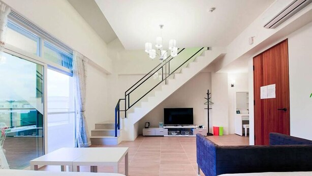 A modern living room with a staircase, a flat-screen TV, and a large window. - Rose Cottage B&B (Taitung)