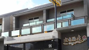 A modern building with a large garage door, a balcony, and a sign that reads "Rose Cottage." - Rose Cottage B&B (Taitung)