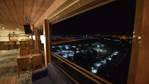 Een hotelkamer met een groot raam met uitzicht op een stadsbeeld bij nacht.