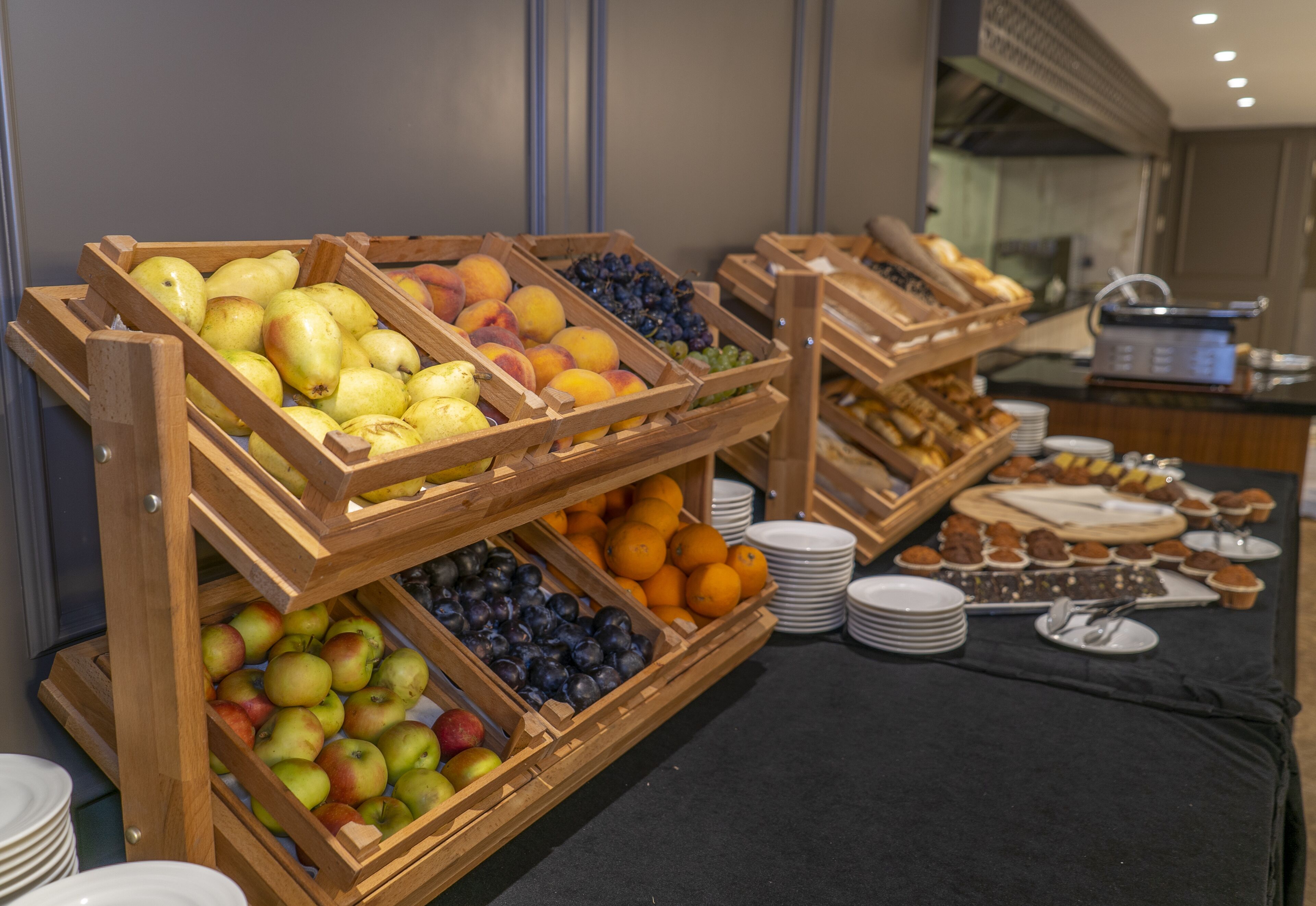 A buffet with wooden crates of fruits and pastries.