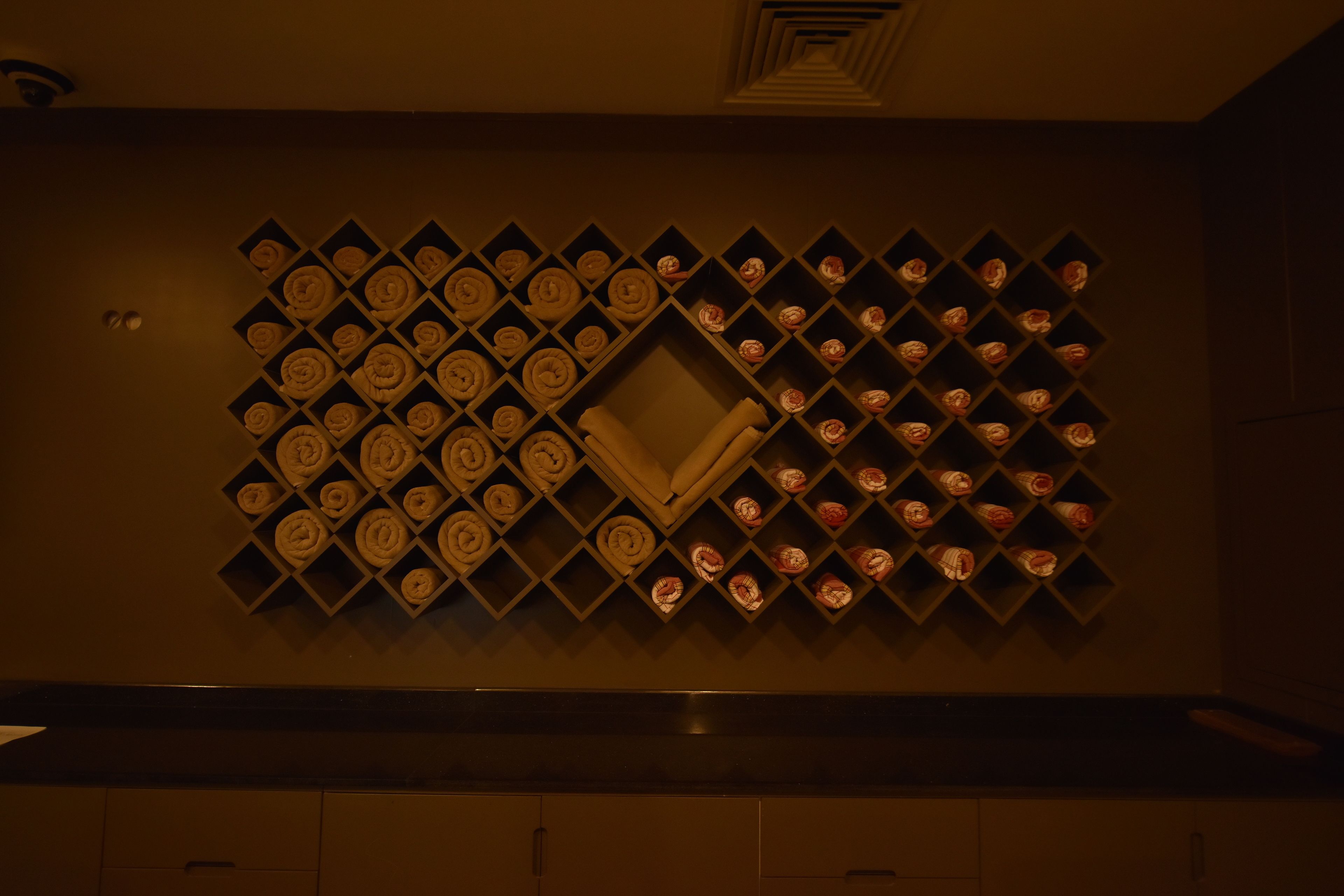 A wall with a geometric pattern of shelves holding neatly folded towels.