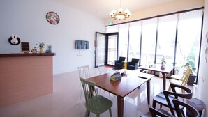 A modern dining area with a wooden table, chairs, and a chandelier. - Man Lu B&B (Hualien City)
