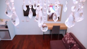 A room with a wooden floor, a brown sofa, and a TV on the wall. - Man Lu B&B (Hualien City)