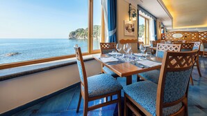 Un coin repas avec une table dressée pour quatre personnes, offrant une vue panoramique sur la côte.