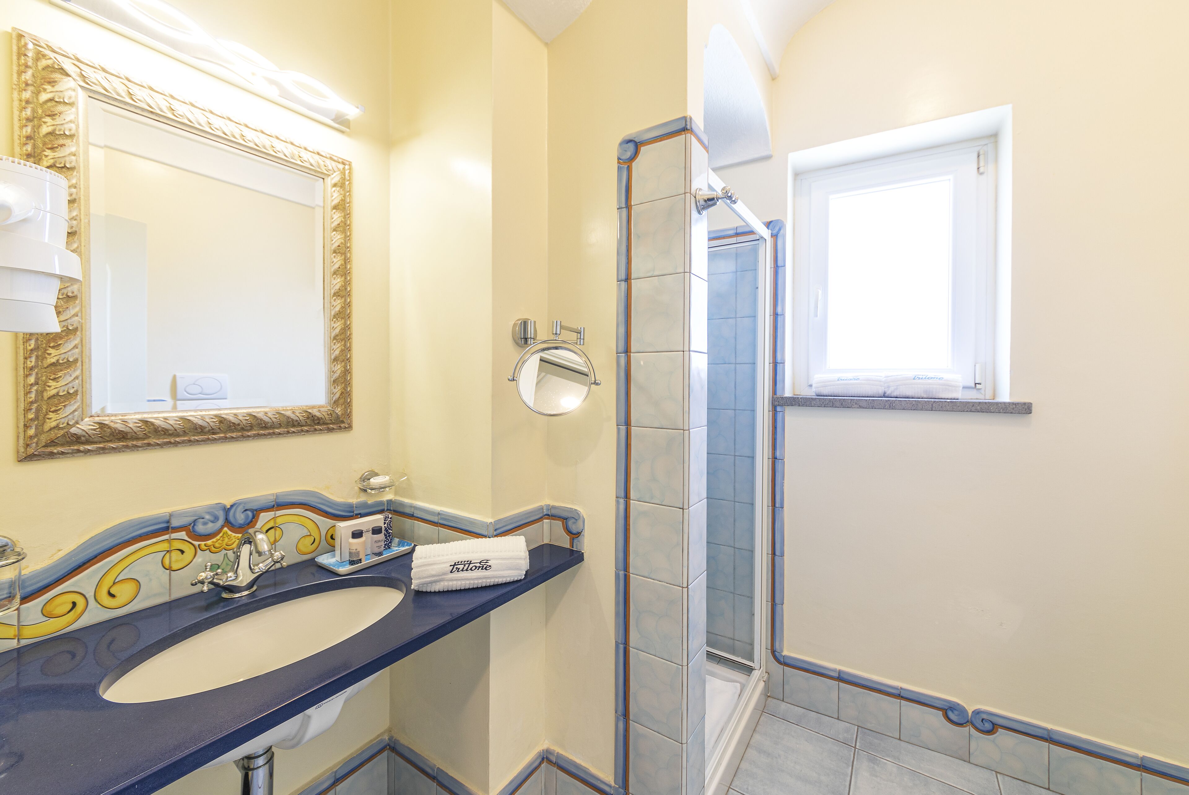 A bathroom with a large mirror, a sink, a towel rack, and a shower area.