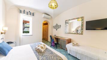 A hotel room with a bed, a desk, a chair, a television, and a window with a view of greenery.