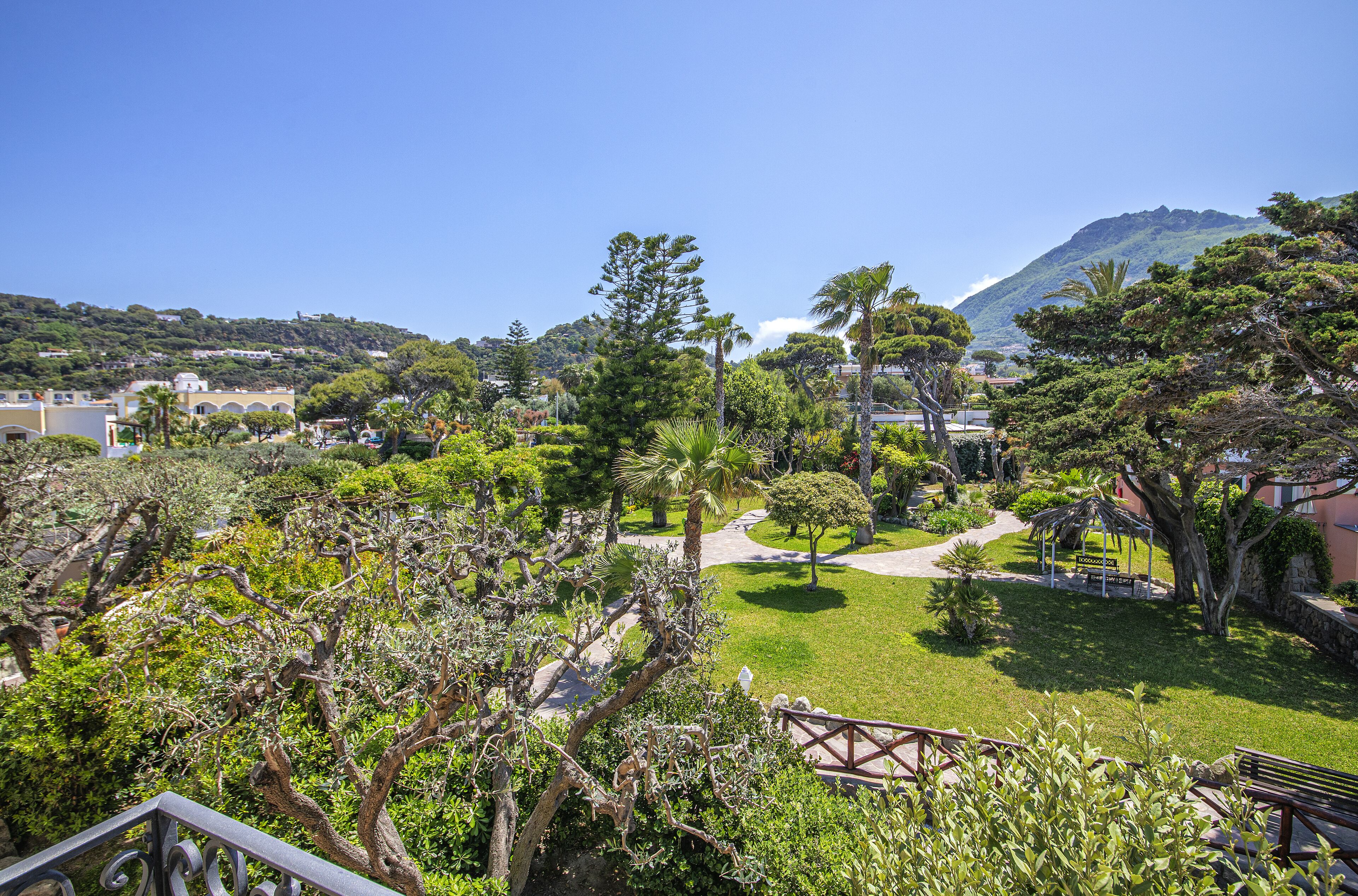 A lush garden with a gazebo, a pathway, and a view of a mountain.