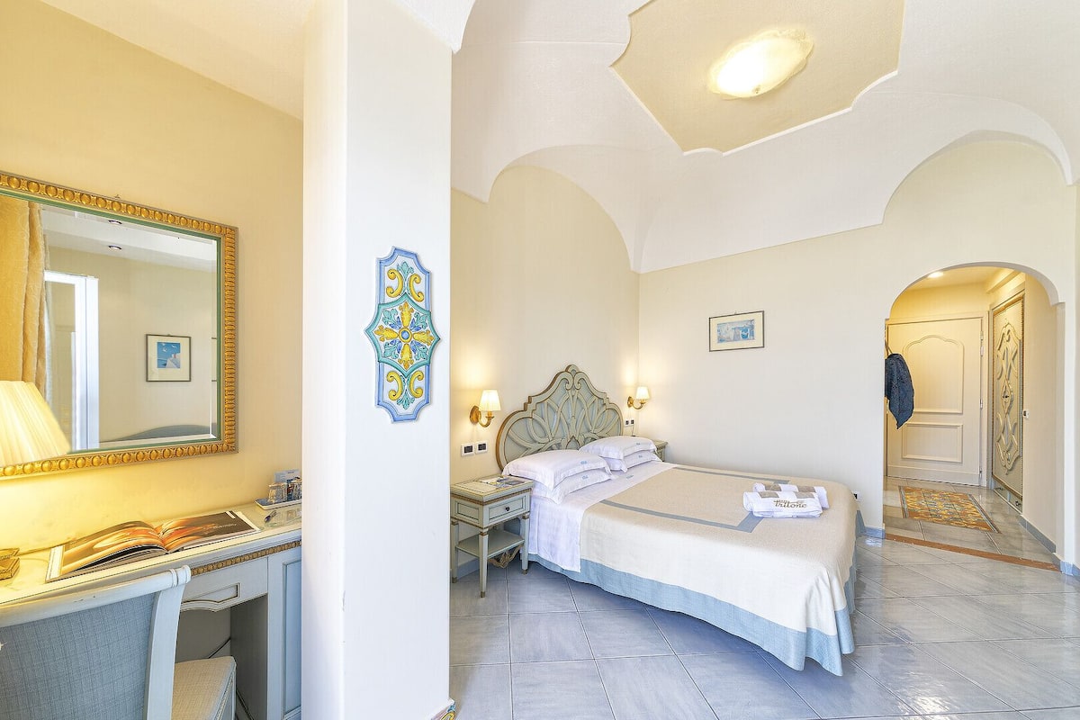 A hotel room with a bed, bedside tables, a mirror, and a decorative wall piece.